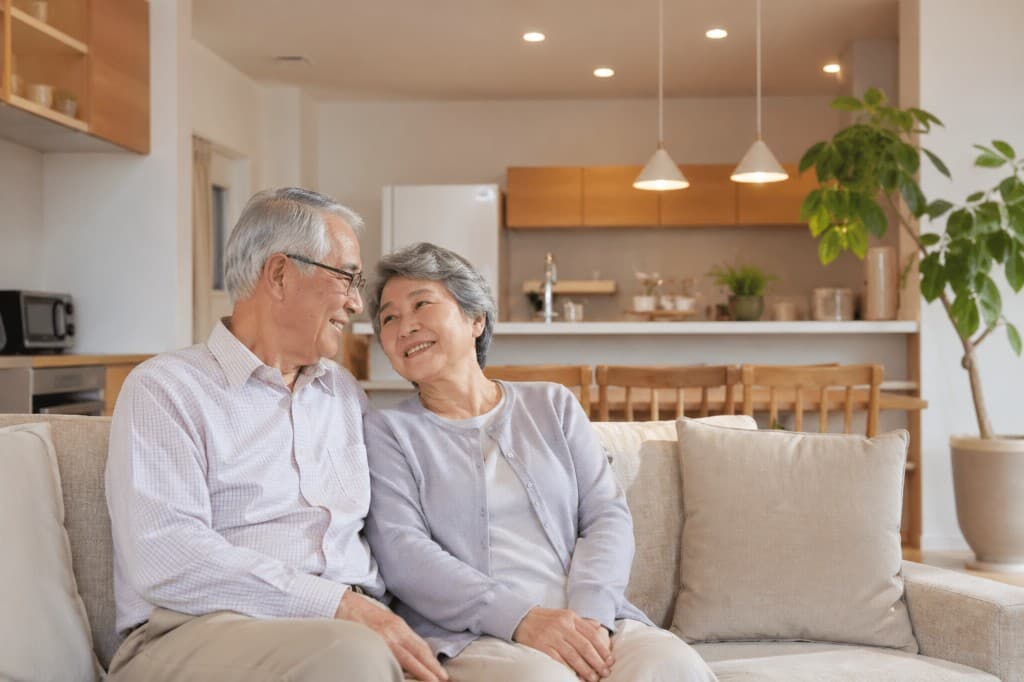 LDKのリビングで70代くらいのご夫婦が見つめ合って微笑んでいる様子
